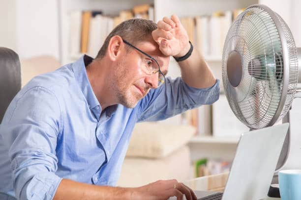 man sweating at home in front of fan